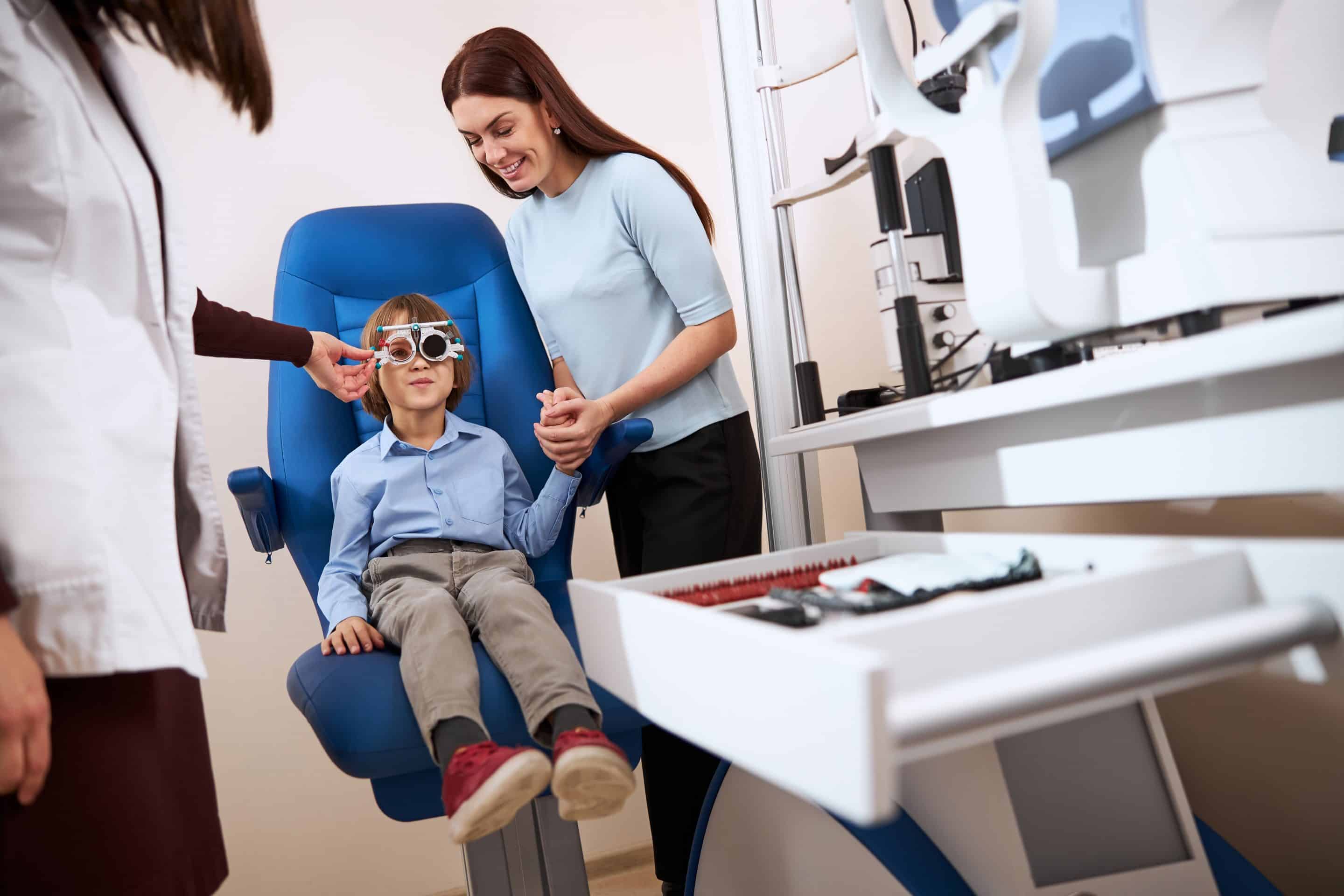 Supportive mother holding boy hand during the eyesight check
